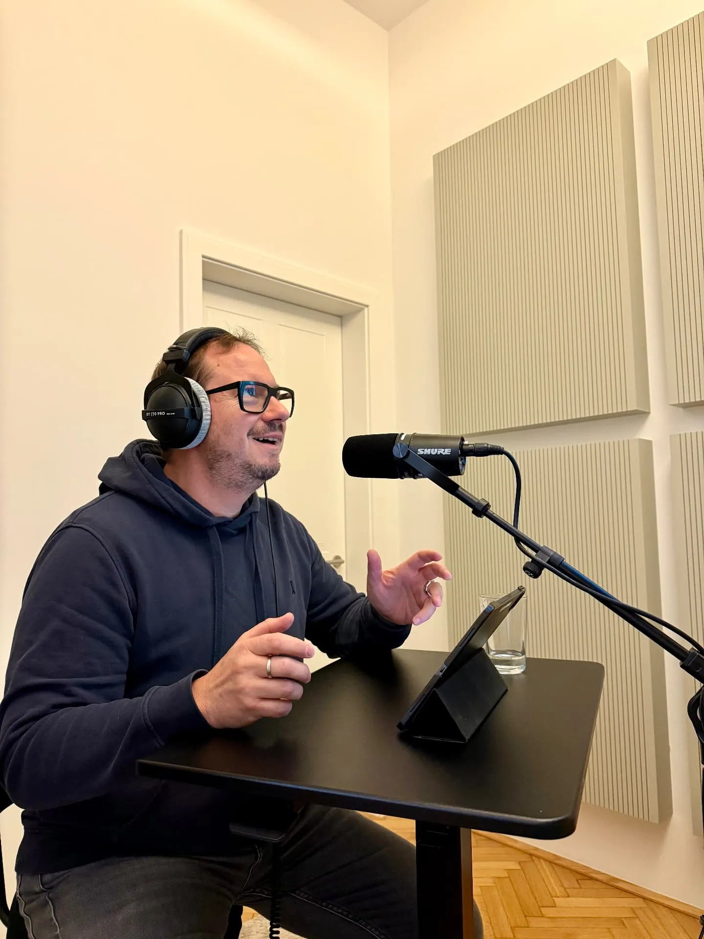 Armin Rogl speaking into a studio microphone wearing headphones